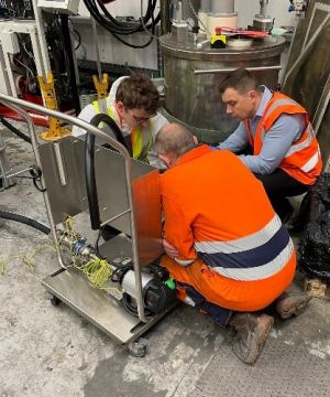Manufacturing workers setting up a drum pump for metering methyl